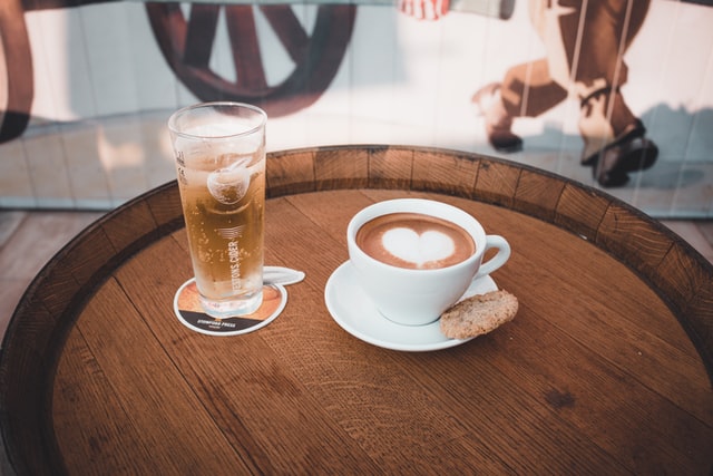 personalised beermats; a glass of chilled beer on a beermat and a cup of coffee placed on a wooden table