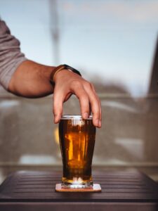 Uses of beermats; a glass of beer on a coaster placed on a table