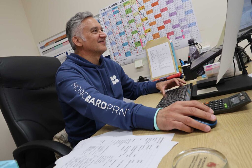 company uniform design, Mosaic BoardPrint employee at desk working