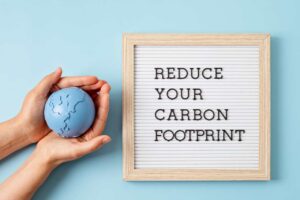 a woman holding a globe saying reduce your carbon footprint